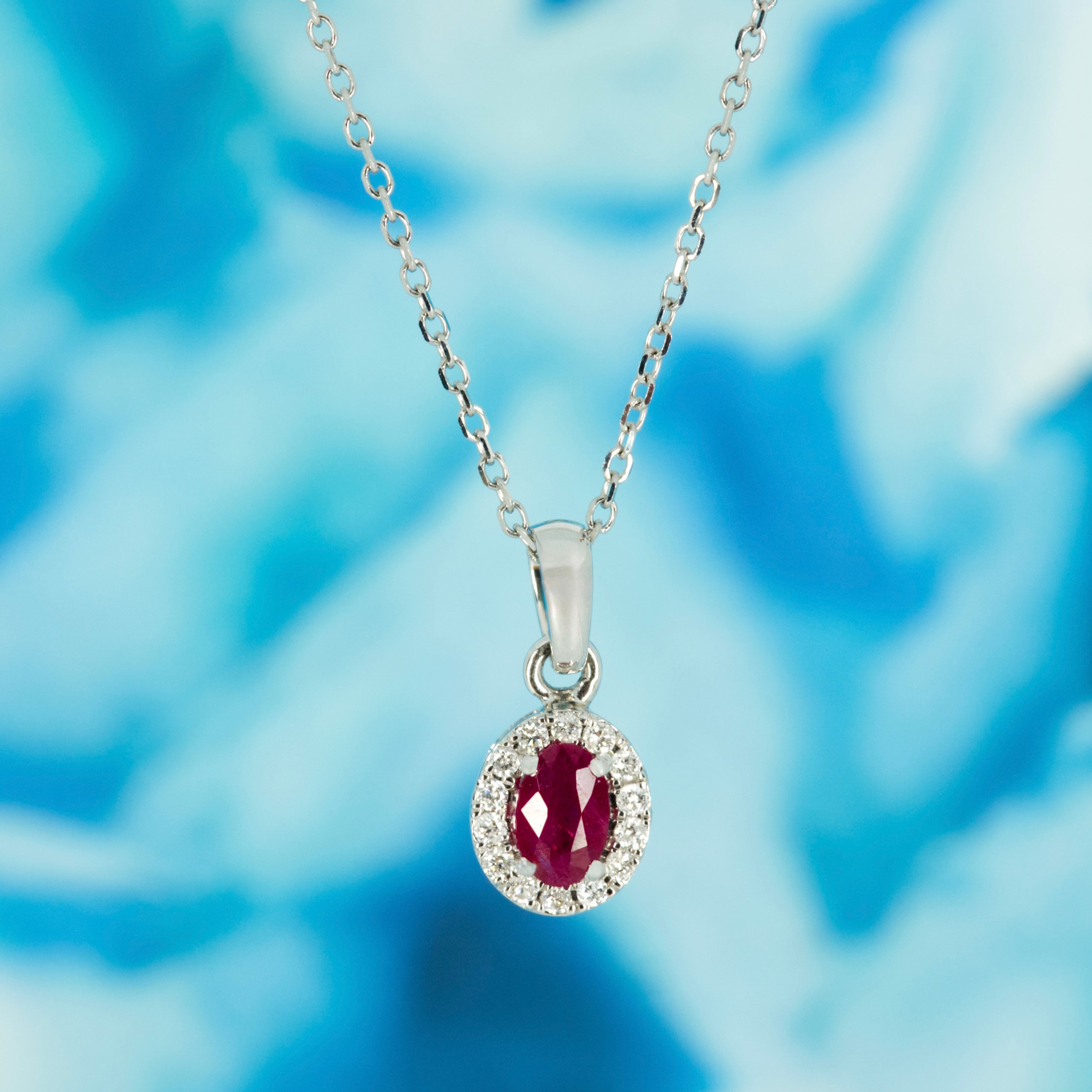 18ct White Gold Oval Cut Ruby & Round Brilliant Cut Diamond Halo Cluster Pendant & Chain