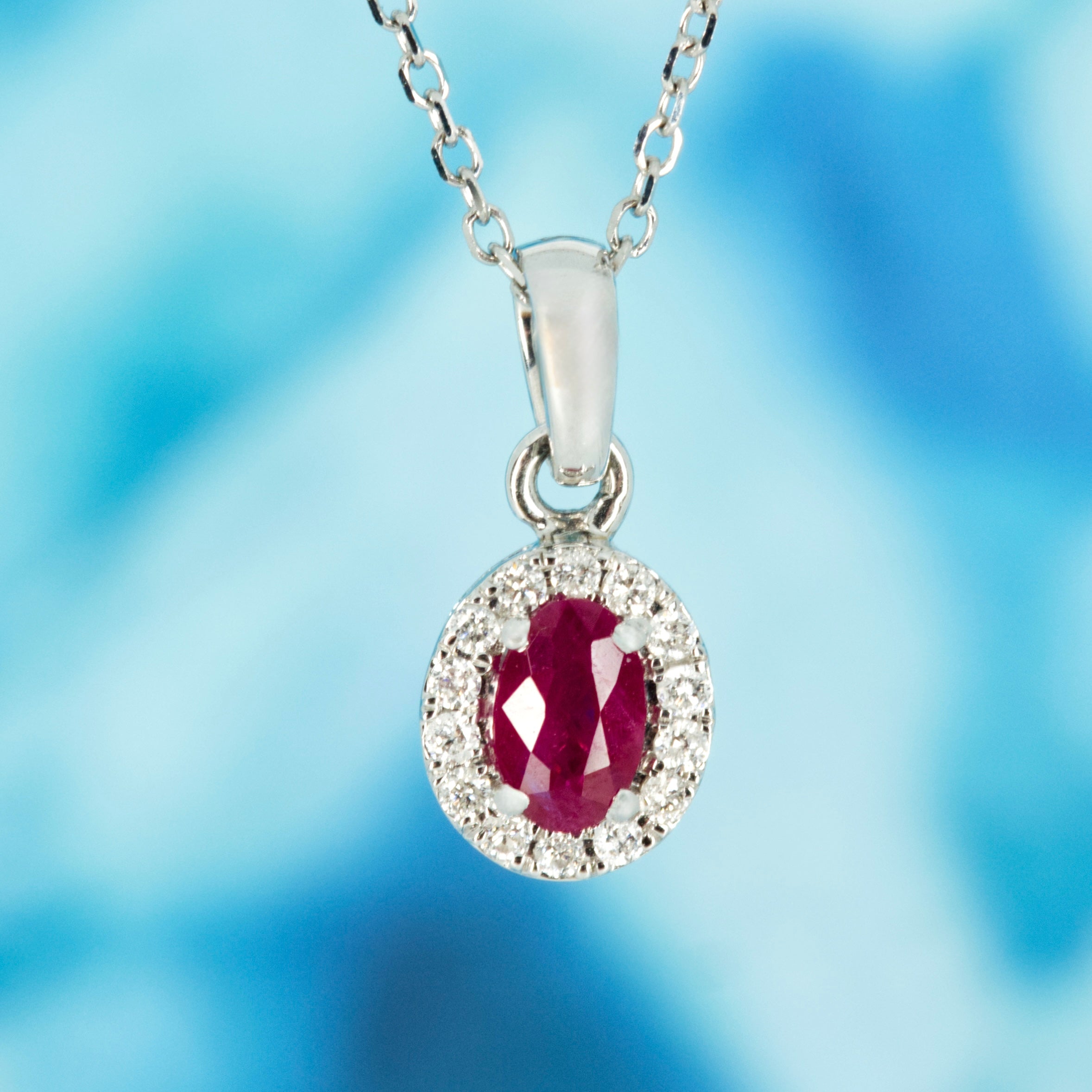 18ct White Gold Oval Cut Ruby & Round Brilliant Cut Diamond Halo Cluster Pendant & Chain